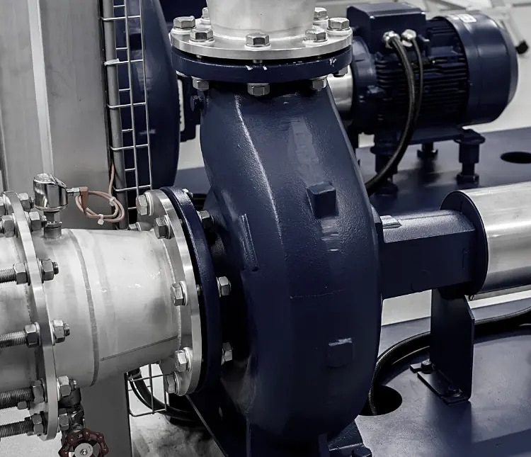 Close-up view of an industrial centrifugal pump with metal piping and an electric motor in a facility setting.